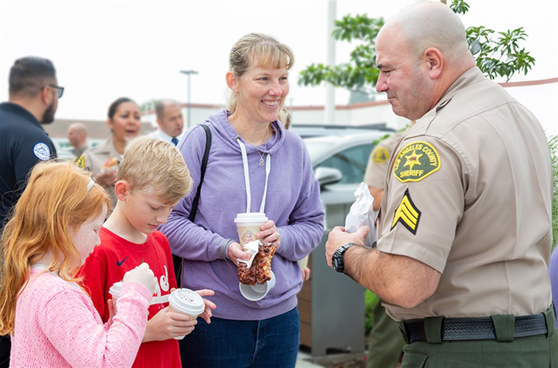 Woman and kids chatting with Deputy Sheriff at donut shop