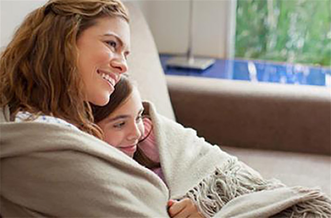 Mom and child snuggling in blankets on the sofa