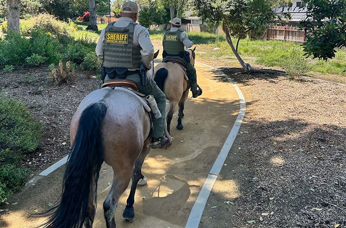 Two Deputies on horses walking down nature trail