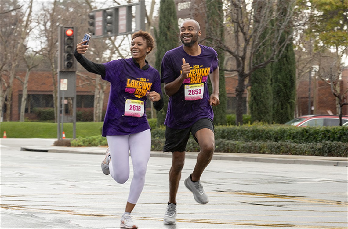 Smiling couple take a selfie while running in the rain at Lakewood Run