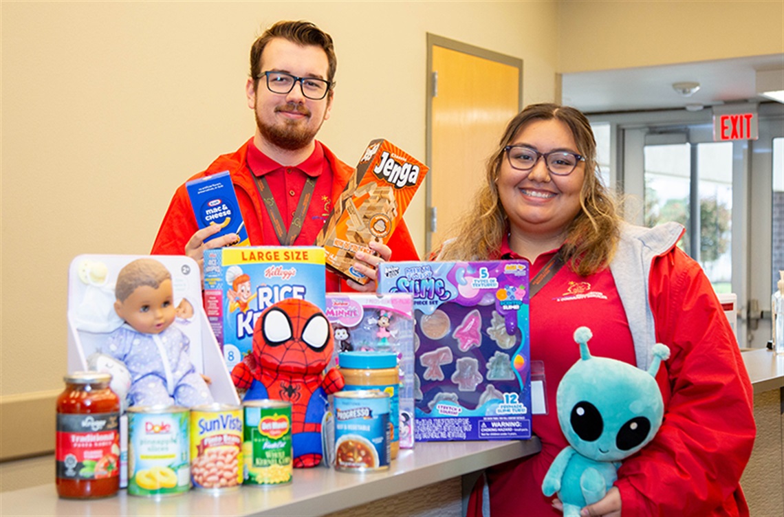 Smiling staff with examples of food and toys for local families in need
